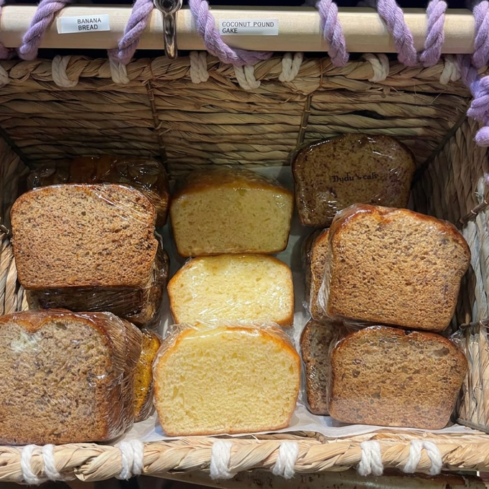 Basket displaying individually wrapped banana bread and coconut pound cake loaves.